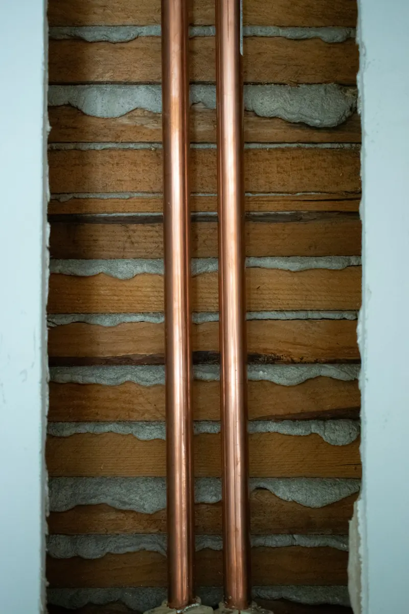 Two new copper supply lines running up through an open wall during rough-in