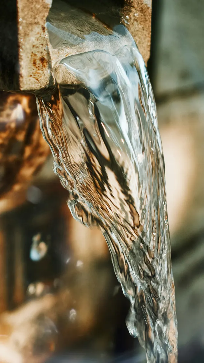 Water pouring from a stone spout in a clear, twisting sheet